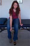 Reiki client sits on massage table and takes off shoes.